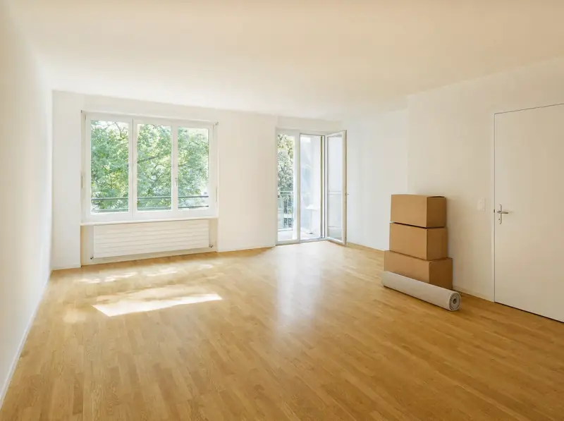 Leere, besenreine Wohnung mit Parkett und Sonnenlicht nach einer Wohnungsräumung